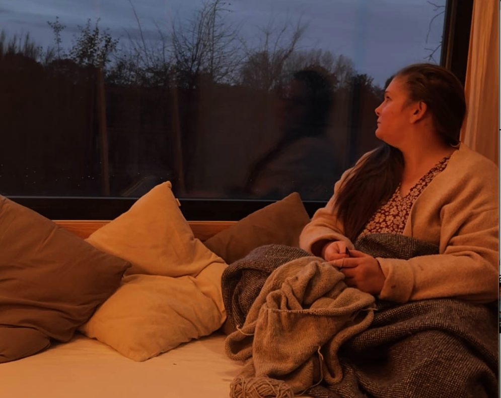 In eine Decke gewickelt auf der Fensterbank in der Dämmerung